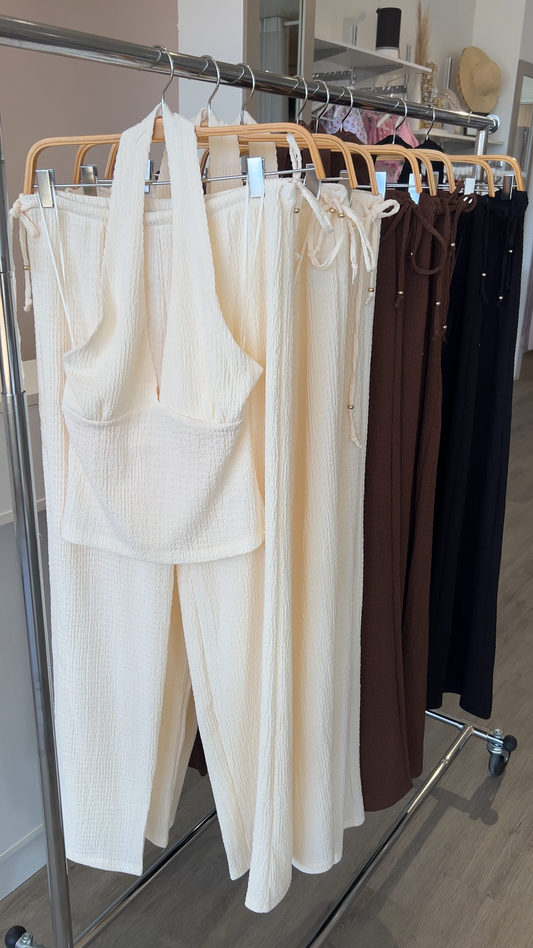 Hangers with cream-colored pants and a beige top on a metal rack.