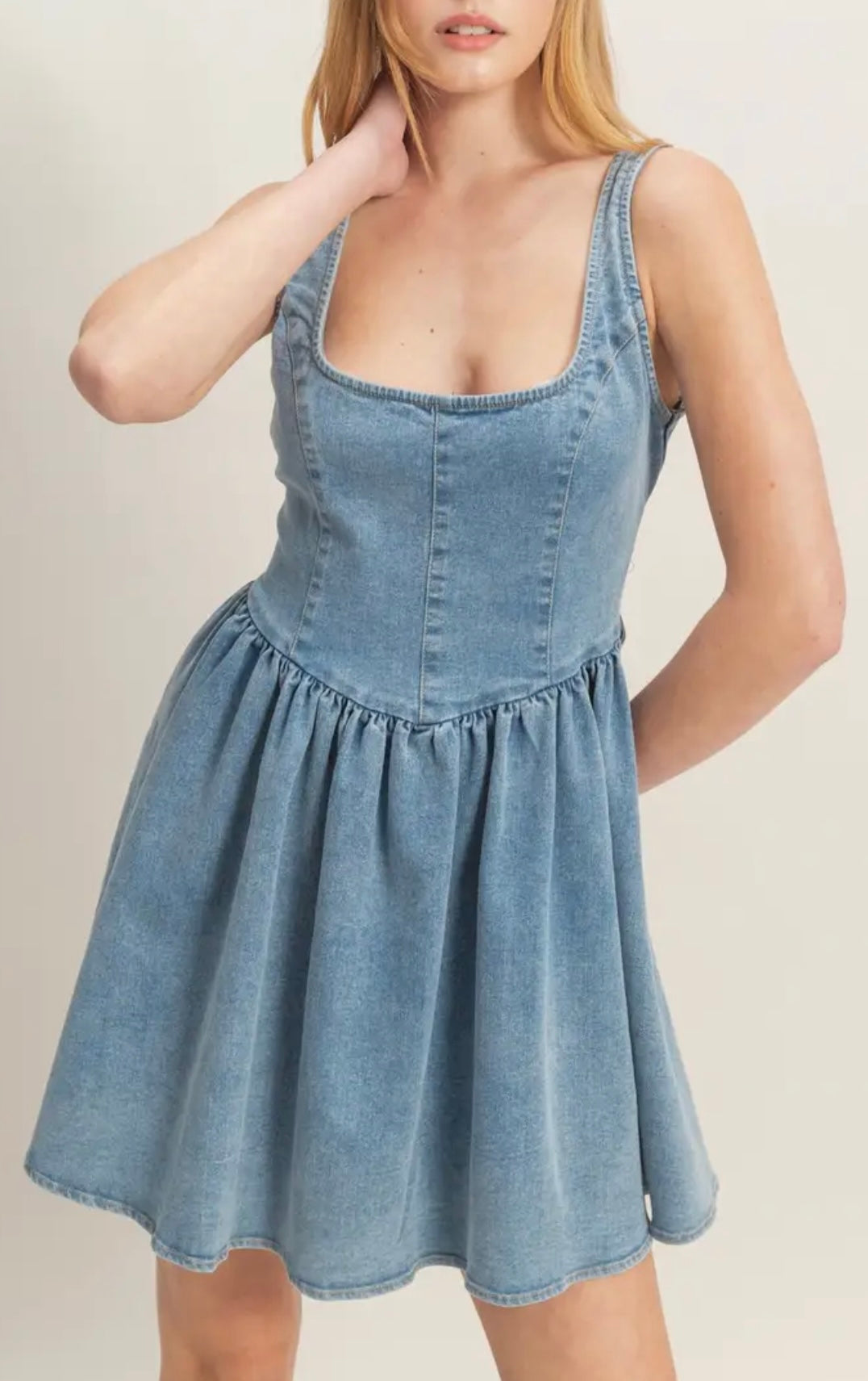 Woman wearing a denim dress against a plain background